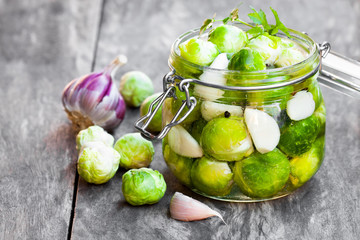 Pickled  Brussels sprouts with garlic in glass jar on wooden tab