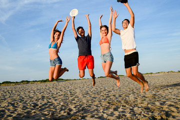 group of young people man and woman jumping on the beach and having fun and party summer sunset holiday vacation