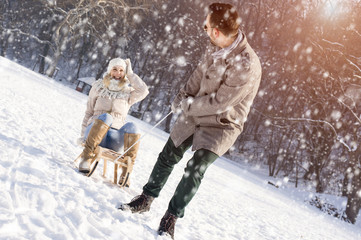 Fototapeta premium Young Couple Sledding And Enjoying While Snow Falling