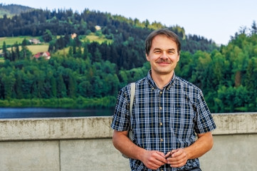 Portrait of a man against a mountain landscape.