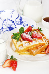Hot homemade belgian waffles with berries and milk on light back