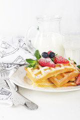 Hot homemade belgian waffles with berries and milk on light back