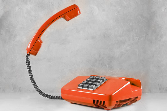 landline red phone on a gray wall background