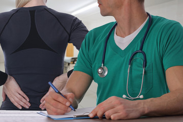 Woman patient suffering from back pain during medical exam by doctor . Rehabilitation after Sports...