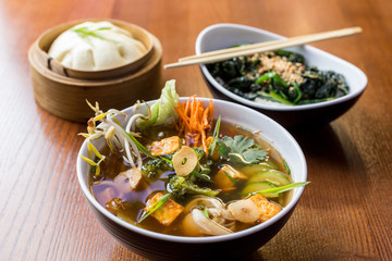 Asian dinner dishes - bao, soup and salad