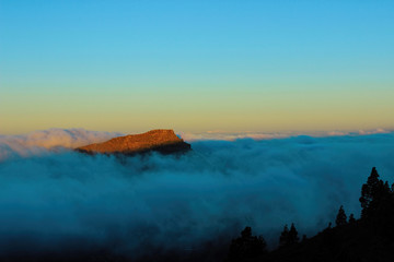 Sunrise above the clouds which illuminates the top of a mountain in Tenerife Island. Canary. Span, Europe