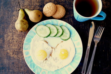 Healthy breakfast, fried eggs, cucumber, fruit, tea