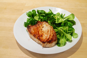 Tuna steak with corn salad on a white plate on a wooden background