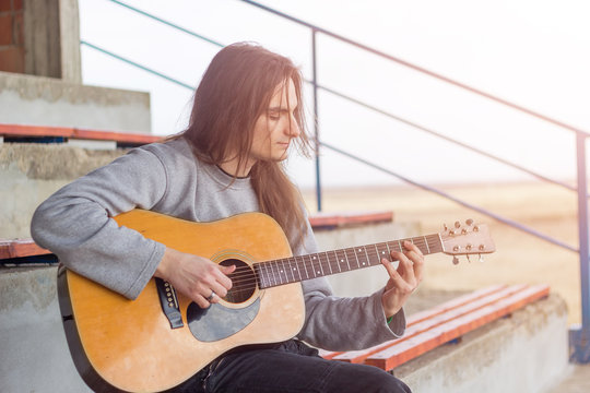 Guitar player playing song outdoor. Lens flare