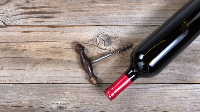 Unopen bottle of red wine with vintage corkscrew on wood