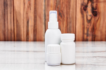 White remedy containers. Medical products on wooden backdrop.