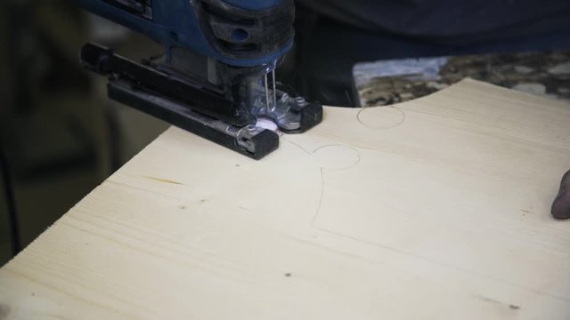 A craftsman is sawing a wooden bar using a fretsaw. Real time close up shot. A concept of master class.