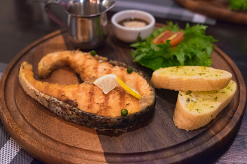 Grilled salmon steak with the fresh salad in white plate.