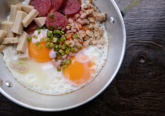 Top view closeup pan fried eggs with spinach breakfast menu in a pan with wooden background, healthy concept.