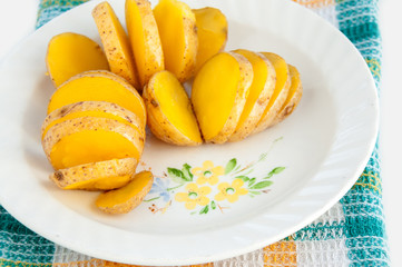 Baked potatoes in their skins yellow on a white plate