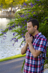 Fototapeta premium Man praying by a lake alone by a pathway.