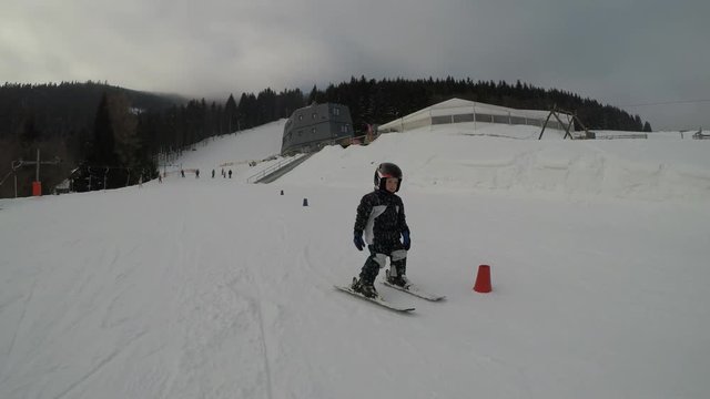 Skiing lessons. Ski school.
Little boy learning to ski. Driving through children's slalom.