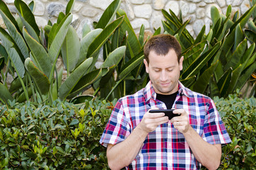 Man outside playing on a smart phone.