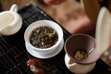Chinese ceramic cup with green tea on wooden tray. Traditional tea ceremony. Soft focus