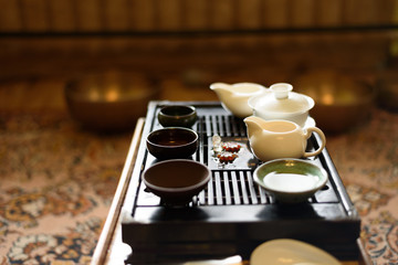 Chinese ceramic cup with green tea on wooden tray. Traditional tea ceremony. Soft focus