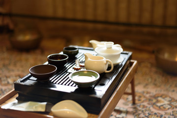 Obraz na płótnie Canvas Chinese ceramic cup with green tea on wooden tray. Traditional tea ceremony. Soft focus