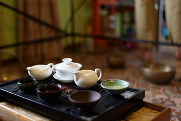 Fototapeta na wymiar Chinese ceramic cup with green tea on wooden tray. Traditional tea ceremony. Soft focus