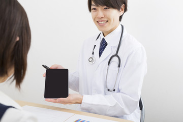 Fototapeta premium 医者 病院 打ち合わせ 汎用 イメージ 室内 タブレット 説明 対面 資料 カウンセリング