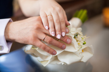 Obraz na płótnie Canvas Hands of bride and groom on wedding bouquet. Marriage concept