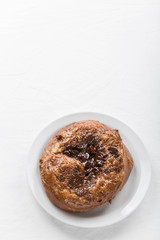 A chocolate custard bun on a white plate. Vertical layout. Copy space 