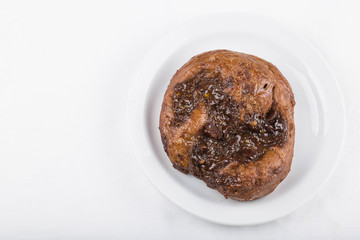 Chocolate custard bun on a white plate, white background. Copy space 