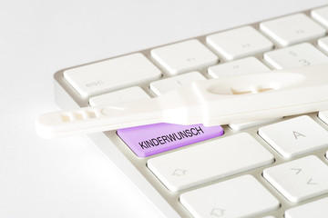Ein Schwangerschaftstest und eine Computertastatur mit der Taste Kinderwunsch