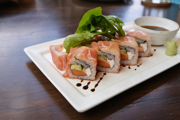 fusion salmon sushi rolls with sauce on white plate; healthy and