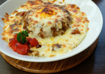 closeup baked spinach with cheese with dill and pickles in white bowl on tray wooden.