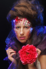 young woman with artistic visage holding big red flower