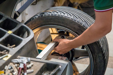 Fototapeta premium Car mechanic, Professional car mechanic changing car wheel in auto repair service.