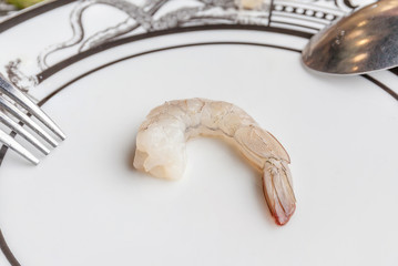 A raw fresh shrimp served on luxury ceramic plate with spoon and