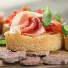 Bruschetta with prosciutto and basil on a wooden table