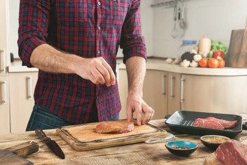 Crédence de cuisine en verre imprimé Cuisinier Man cooking grilled steak on the home kitchen