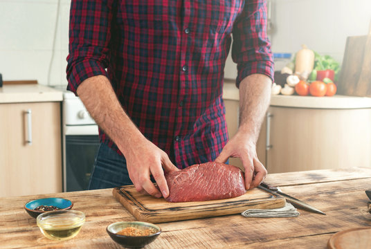 Man holding of piece of beef meat on a wooden table