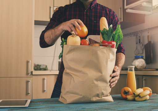 Man examines a paper bag with different healthy food