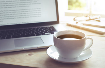 Cup of coffee on wooden desk with laptop and notebook. inspirati