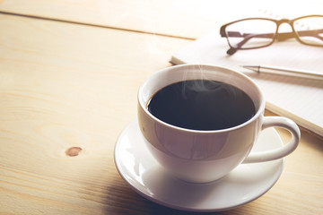 Cup of coffee on wooden desk with pen and notebook. inspiration