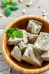 Halva of sunflower seeds and mint in a round wooden bowl.