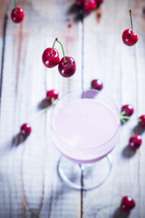 Falling cherries on a table with cherries and glass of smoothie