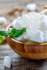 Figured white sugar in wooden bowl close up.
