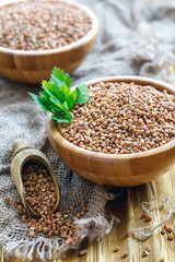 Bowl and a wooden scoop with raw buckwheat.