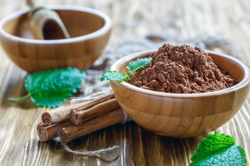 Wooden bowl with the cocoa powder and cinnamon sticks.