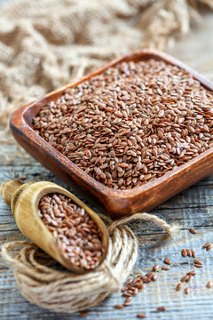 Brown flax and wooden scoop in a square bowl.