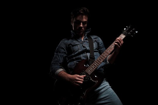 young sexy man playing an electric guitar with passion