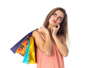 a young girl looks thoughtfully to the side and holding  multicolored bags